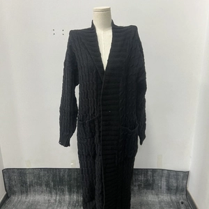 Dettaglio di un cardigan lungo nero con trama a trecce spesse e design della tasca laterale