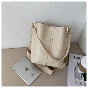 Detail of cream bucket bag with crocodile pattern and wide canvas shoulder strap