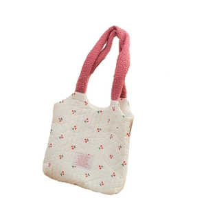 Detail of cherry print quilted canvas bag with soft pink sherpa handle and fabric label
