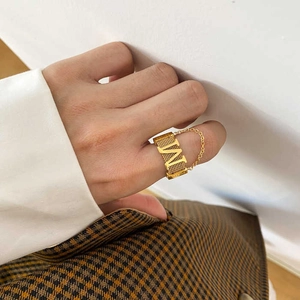Close-up of gold M-letter ring with chain design worn on finger for a stylish look