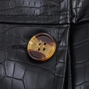 Close-up of black crocodile embossed PU leather coat featuring amber resin buttons