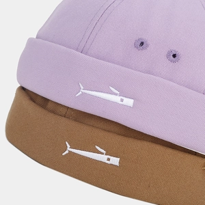 Close-up of small fish embroidery on textured cotton docker hats in purple and brown