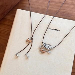 Détail du pendentif cheval en bois et breloques étoilées sur un collier marron