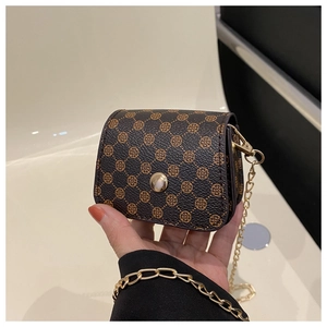 Detail view of small dark brown square bag with clover pattern and metal chain strap