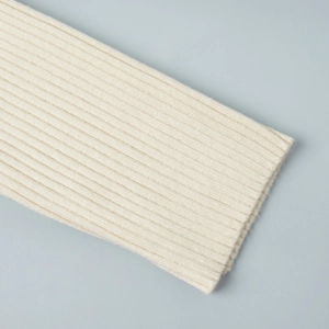 Detailed macro view of the cream ribbed knit texture and cuff stitching on the dress