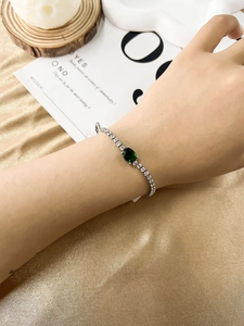 Detail of emerald green crystal tennis bracelet with cubic zirconia on female wrist