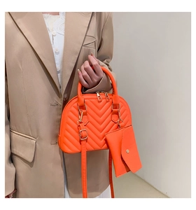 Détail du sac orange en forme de coquille avec surpiqûres en V et zip métallique doré