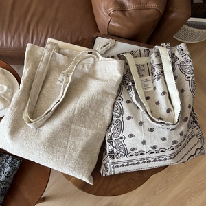 Macro view of minimalist cotton linen tote bags in plain beige and paisley print styles