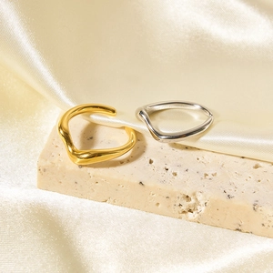 Close-up of minimalist irregular wave rings in 18K gold and silver on a stone tray