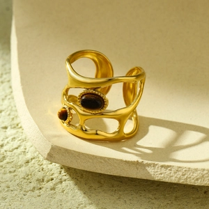 Detail view of gold open ring with irregular cutouts and brown tiger eye stones