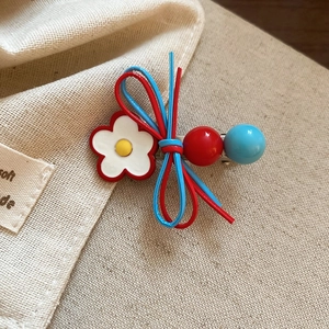 Detail of floral leather bow hair clip with high-shine beads on textured linen background
