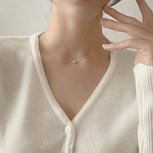 Close-up of minimalist 925 sterling silver necklace with 8mm round bead on a female model