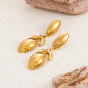 Detailed view of dual teardrop 18K gold plated earrings on a textured stone background