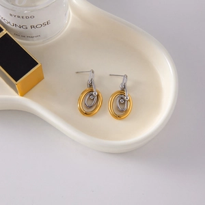Detailed close-up of mixed gold and silver interlocking hoop earrings on a ceramic tray