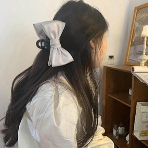 Detail of elegant beige satin bow hair claw clip styled on long hair for a gentle look