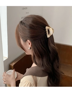 Detail of a large cream acetate hair claw clip styled in a half-up ponytail on a model
