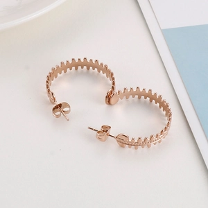 Detailed macro view of rose gold C-shaped earrings with a textured fishtone design