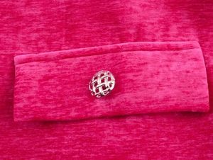 Detailansicht der rosaroten Chenille-Stoffstruktur und des silbernen Netzknopfes