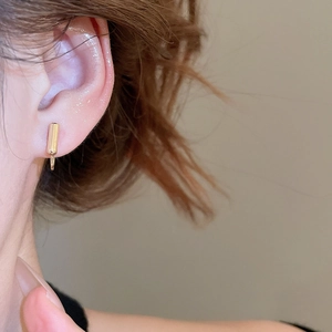 Close-up of golden geometric bar clip-on earring on ear with adjustable screw back mechanism