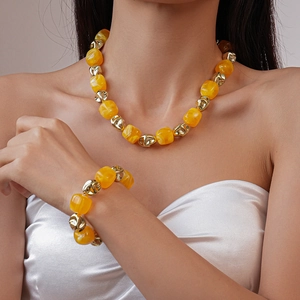 Detail of yellow acrylic geometric beads necklace and bracelet set on model
