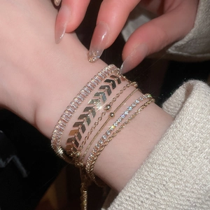 Detailed view of multilayer gold bracelet set with zircon and snake chain on wrist