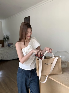 Close-up of khaki straw tote bag with Paris lettering in a cozy indoor setting