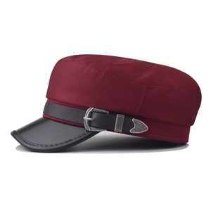 Detail of burgundy military cap featuring a silver metallic buckle and black leather brim