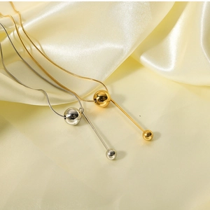 Detail of gold and silver sphere pendant necklaces on smooth silk fabric background