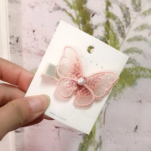 Detailed view of pink embroidered mesh butterfly hair clip with a pearl bead detail