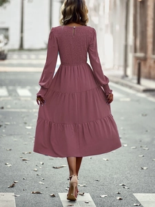 Vue arrière d'une robe midi rose à volants avec dos smocké sur une rue jonchée de feuilles