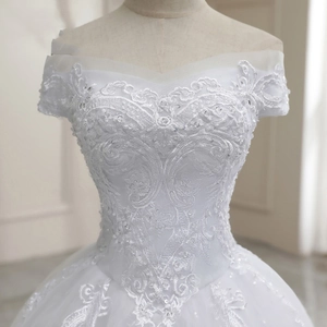 Detailed view of intricate white lace embroidery and sequins on off-shoulder wedding dress