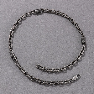 Detail of silver stainless steel chain necklace with unique coils and lobster clasp