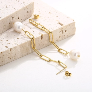 Détail de boucles d'oreilles perles plaquées or 18 carats sur fond de pierre texturée