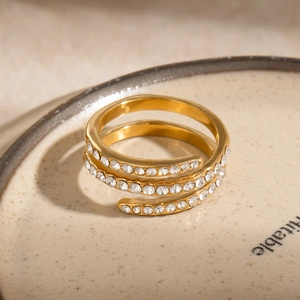 Close-up of 18k gold plated spiral ring with shimmering clear crystals on ceramic plate