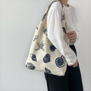 Minimalist canvas tote bag with navy blue starfish print worn by a female model