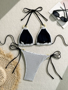 Flat lay of black and white crochet bikini set with yellow accent rings and beach accessories