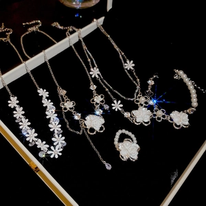 Macro view of floral zircon necklace set with white pearls and tassels on black background