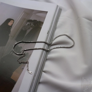 Detail of silver 925 tennis necklace with zircon stones on a lifestyle magazine background