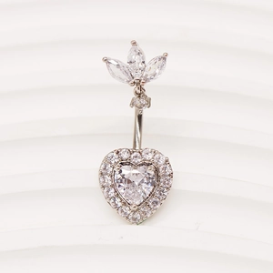 Détail macro du piercing de nombril en argent avec zircon coeur sur fond blanc ondulé