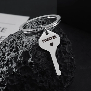 Stainless steel forever heart key keychain on a textured dark rock background