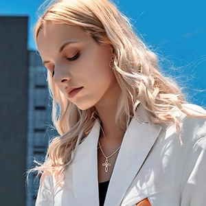 Macro detail of the silver hollow cross pendant necklace on a model with blue sky background