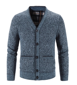 Details einer blauen Strickjacke mit klassischem Karofutter und aufgesetzten Taschen