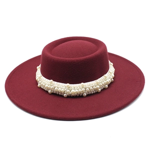 Detail of burgundy boater hat featuring elegant faux pearl headband decoration