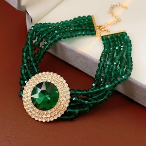 Macro shot of green faceted bead bracelet with large emerald gemstone and gold clasp