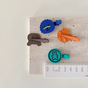 Detailed size measurement of cartoon hair clips on stone background with a ruler