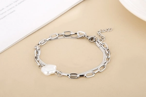 Close-up of silver double-layered snake chain bracelet with white flower pearl charm