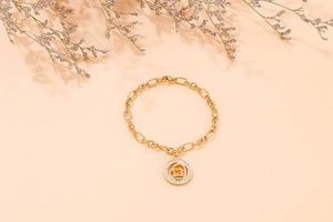 Macro view of gold chain bracelet featuring a round pendant with heart and star cutout