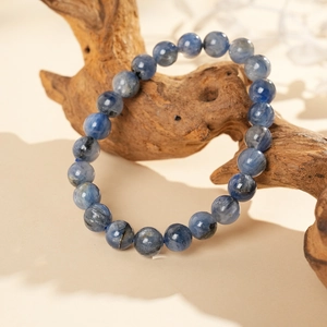 Close-up of deep blue round bead bracelet on a natural wood stand with warm background