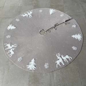 Detail of knitted Christmas tree skirt featuring reindeer and snowflake embroidery with ties