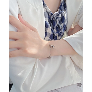 Detail shot of heart-shaped shell pendant on silver stainless steel bracelet on wrist